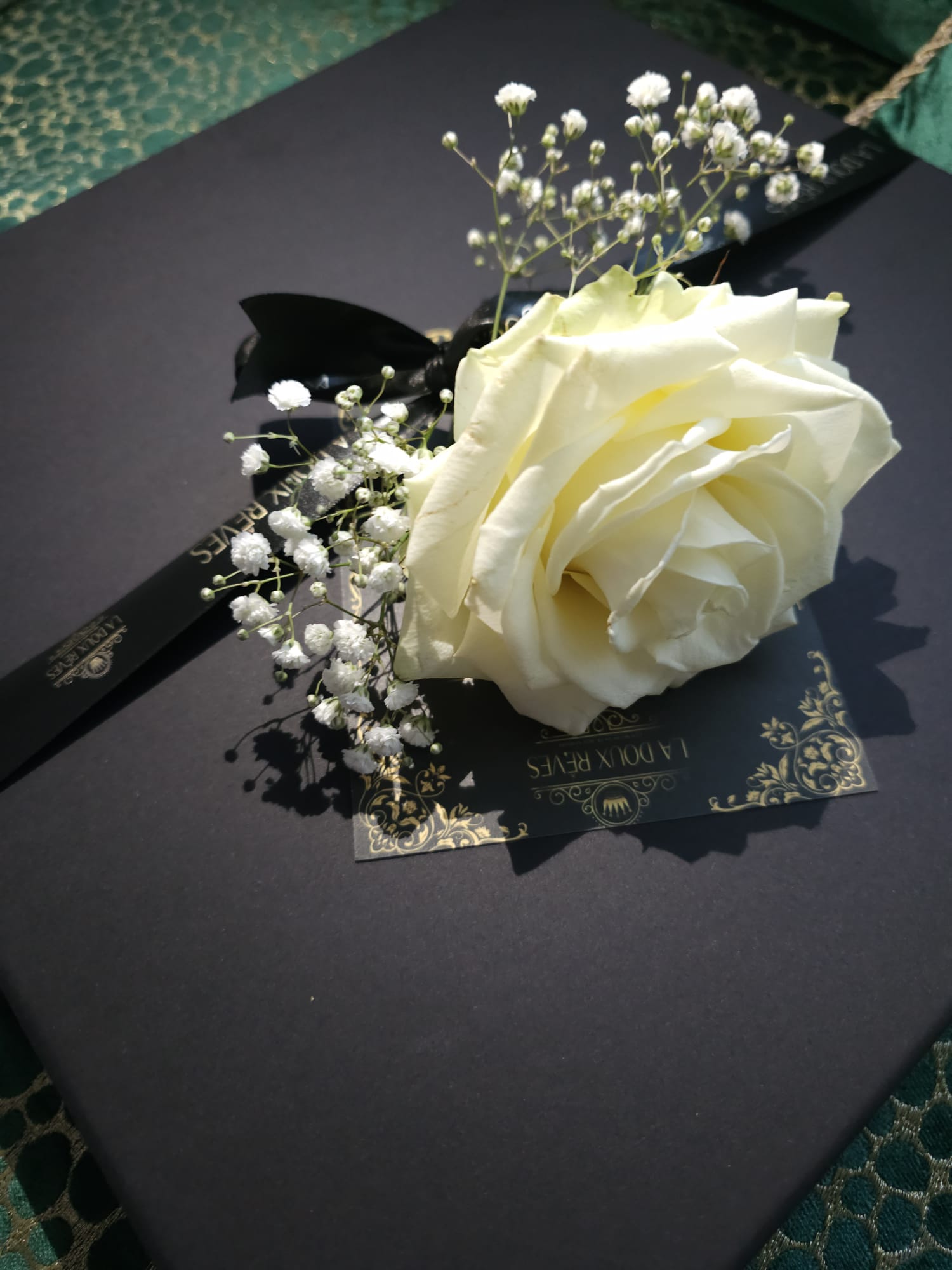 Witte roos en gipskruid op zwart boek.